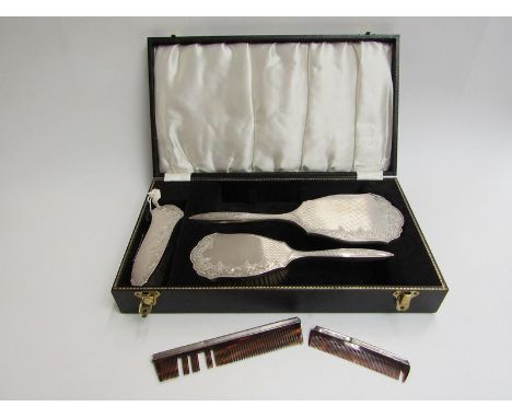 An Elizabeth II silver backed four piece dressing table set of hand mirror, hair brush, clothes brush and comb, with engine t