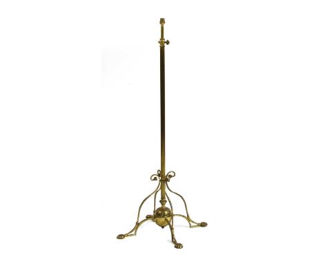 An Arts and Crafts brass standard lamp,with a reeded shaft, extendable, on four scrolled supports,128cm high approximatelyCon