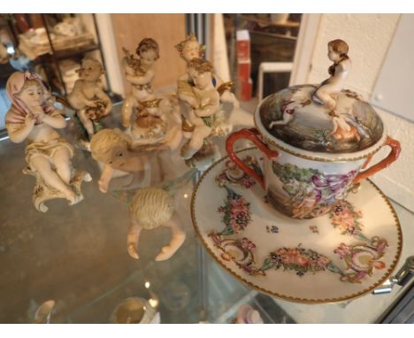 Collection of ceramic cherub and putti figurines and a cherub decorated hot chocolate cup