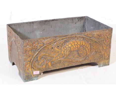 A large Chinese metal embossed planter of rectangular form with floral dragon design across the sides with green glass eyes. 