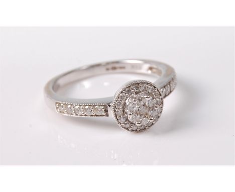 An 18ct white gold diamond ring, the central cluster of small round brilliant cut diamonds, with halo diamond surround in mil