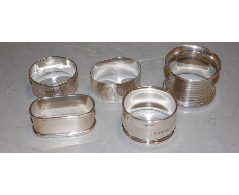 Four various silver napkin rings, with engine turned decoration; and a plated example (5)