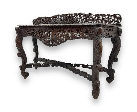 Late 19th century Anglo-Indian heavily carved hardwood console table, serpentine top with carved edge, back gallery profusely
