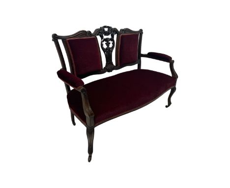 Late Victorian stained beech framed sofa, the backrests, seat and padded arms upholstered in deep red fabric, carved crest ra