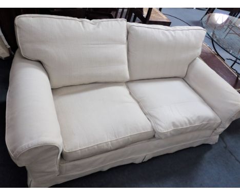 A TWO SEATER SOFA, WITH CREAM LOOSE COVERS over rich kilim style fabric upholstery 190cm long