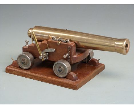 Signalling or display model cannon with 33cm graduated brass barrel raised on oak carriage and further oak plinth, 36cm long.