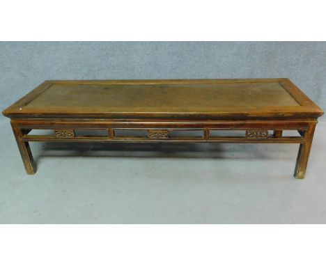 A Chinese teak low table with rattan inset top above carved frieze on square section supports. H.50 W.197 D.67cm 