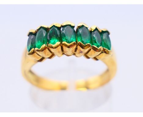 An 18 K gold emerald seven-stone row ring. Ring size O.