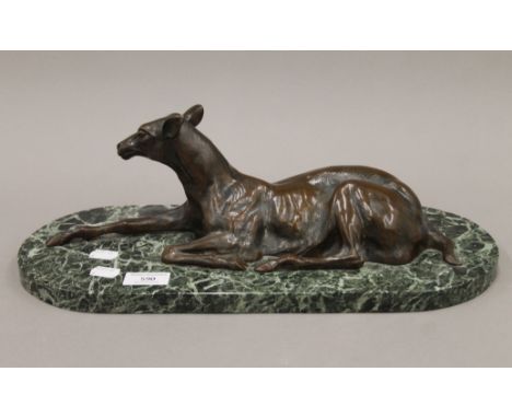 A large patinated bronze model of a fawn mounted on a variegated green marble base. 43 cm long.