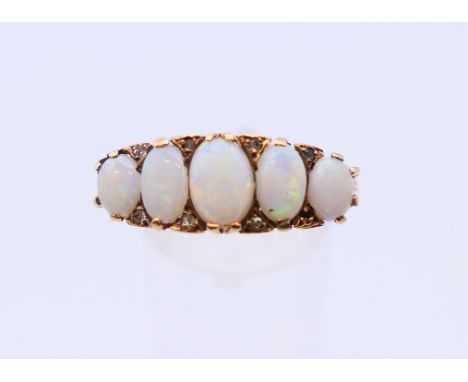 A 9 ct gold ring set with five opals.  4.1 grammes. Ring size U.