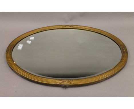 A gilt-framed bevelled oval wall glass/mirror. 66 cm wide.