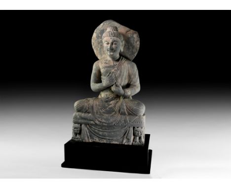 4th-5th century AD. A large carved schist figure of Buddha sitting cross-legged on a dais, hands raised to the chest in the d