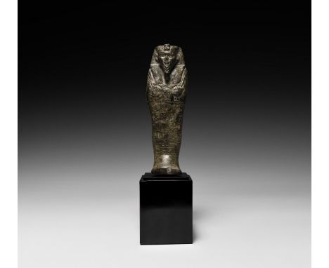 Napatan Period, 643-623 BC. A rhyolite shabti with mummiform body, arms crossed over the chest, the right hand holding a narr