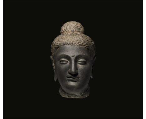 2nd-3rd century AD. A carved schist head of Buddha with ushnisha and urna to the brow.  19.4 kg, 33cm (13"). Property of a Mi