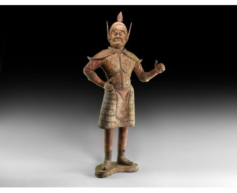 Tang Dynasty, 618-906 AD. A substantial ceramic figure of a guard standing on a crescent base, wearing a domed helmet with sp