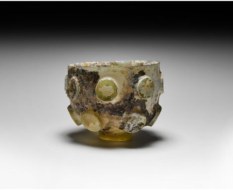 6th-7th century AD. A cut glass cup with button base and two rows of scooped button ornaments to the sidewall. Cf. similar it