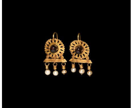 2nd century AD. A matching pair of gold earrings, each an openwork disc with a central spherical garnet bead and hook to the 