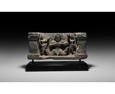 2nd-3rd century AD. A carved schist frieze panel with facing anguipede playing a stringed musical instrument flanked by danci