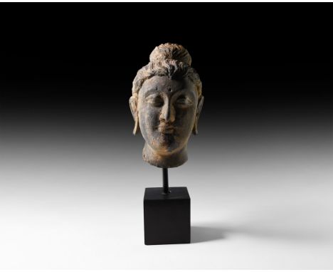 2nd-3rd century AD. A carved schist bust of Buddha with detailed wavy hair, ushnisha, long earlobes, hooded eyes and urna to 