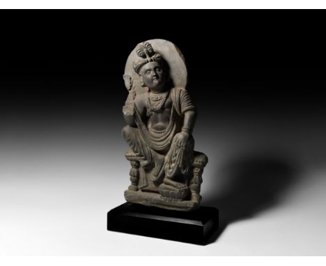 2nd-3rd century AD. A carved schist figure of bodhisattva Shakyamuni on a bench with lotus footstool,&nbsp;aureole to the rea