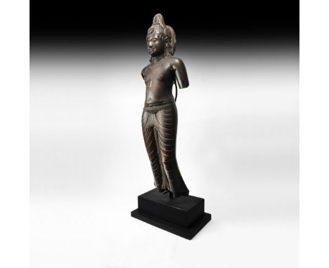 7th-10th century AD. A carved stone statue of Avalokite?vara in male form, nimbate, wearing a tight-fitting dhoti and decorat