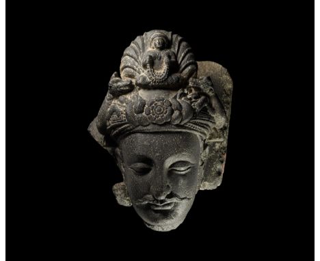 3rd-4th century AD. A carved porphyritic basalt head of a bodhisattva with neat moustache and elaborate turban ornamented wit