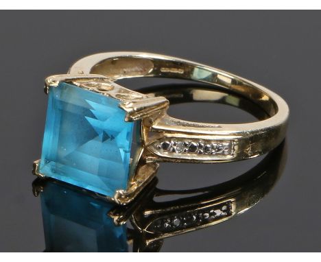 9 carat gold blue topaz and diamond ring, the square topaz flanked by a small diamond to each shoulder, ring size O 1/2, 3.3g