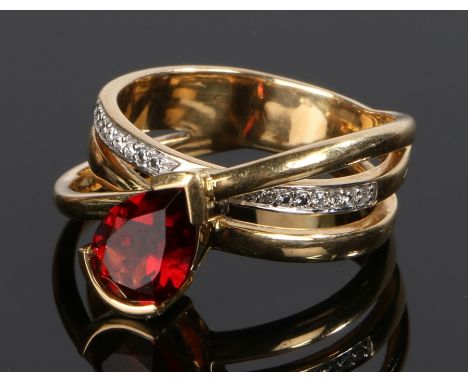 18 carat gold garnet and diamond set ring, with a cross over shank set with a pear cut garnet and a row of diamonds, 9.7 gram