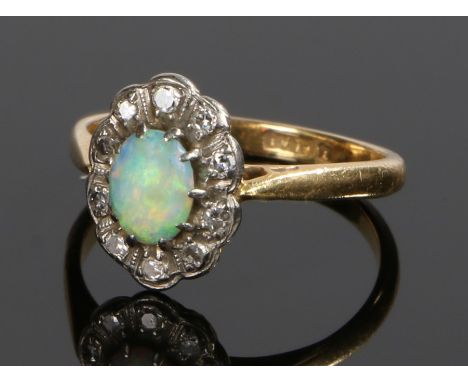 18 carat gold opal and diamond ring, the central oval opal surrounded by a band of diamonds, ring size K 1/2, 2.7g