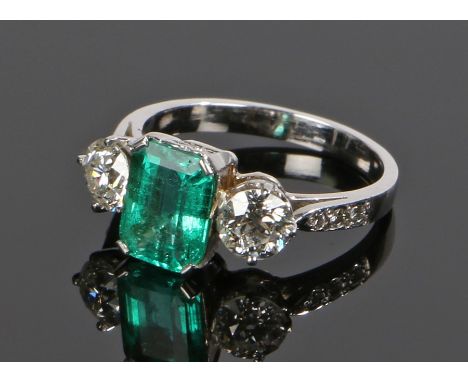 Columbian emerald and diamond set ring. The central certificated 1.55 carat natural emerald flanked by a diamond to either si