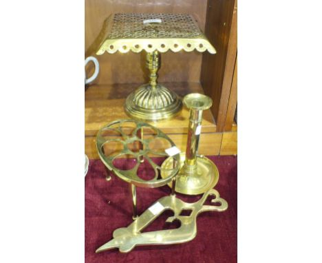A brass trivet with pierced square top, 21.5cm high, two other trivets and a candlestick, (4).
