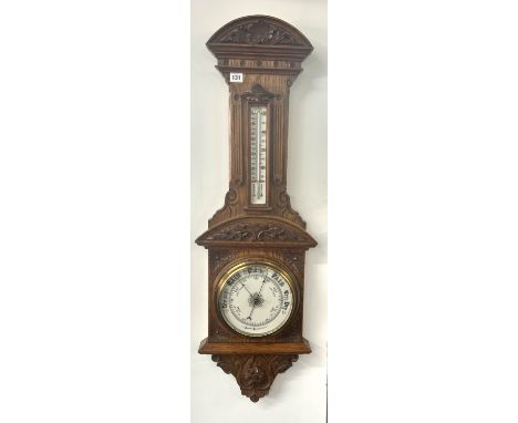 An early 20th century carved oak wall Aneroid Barometer with thermometer, length 102cm.