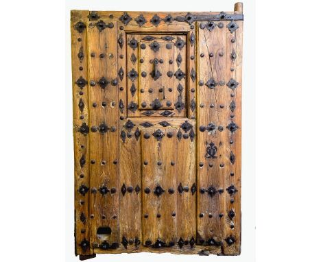 A monumental 17th-18th century Spanish walnut door, probably walnut, with applied panels and wrought iron rivet heads, floral