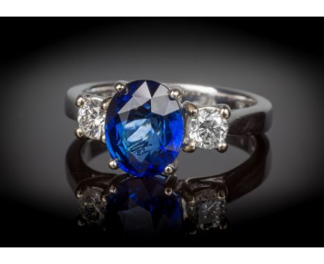 An 18ct white gold, sapphire and diamond three stone ring, the 2.85ct oval cut sapphire of good colour, flanked by two brilli