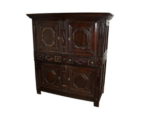 A late 17th / early 18th century two part joined oak press cupboard, possibly American, the later, flared and stepped cornice