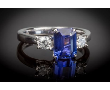 An 18ct white gold, Tanzanite and diamond three stone ring, the emerald cut 2.18ct Tamzanite of good colour, flanked by two b