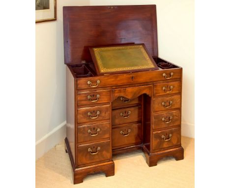 A George III mahogany kneehole desk with lifting top, the unusual lifting moulded edged top revealing centralised green and g