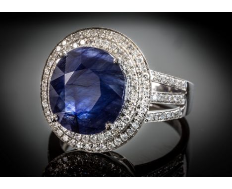 A 14ct white gold, sapphire and diamond cluster ring, the 5.80 ct oval cut sapphire within a double halo of brilliant cut dia