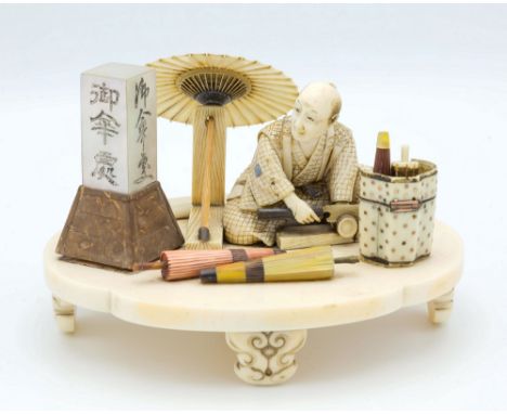 A Japanese carved ivory, Shibayama and mother of pearl okimono of a parasol maker, Meiji period (1868-1912), the diorama on a