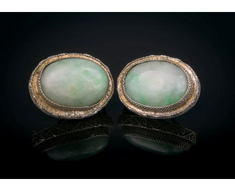 A pair of Oriental silver and jade clip earrings, early 20th century, the oval, white and apple green mottled jade stones in 