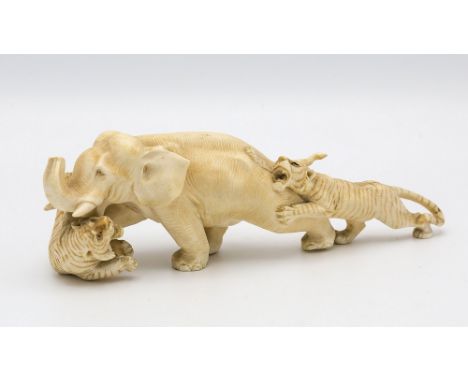 A Japanese carved ivory okimono, Meiji period (1868-1912), carved as an elephant under attack by two tigers, unsigned, 6 5/8i