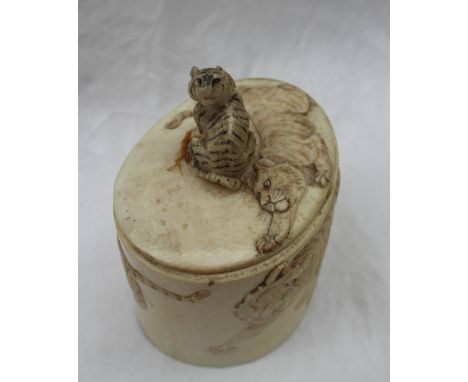 A Japanese ivory box and cover of oval form carved with a tiger finial, the body carved with tigers, signed to the base, 8cm 