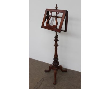 A Victorian mahogany music stand, with a sloping adjustable rest on a telescopic brass column and a turned and carved column 