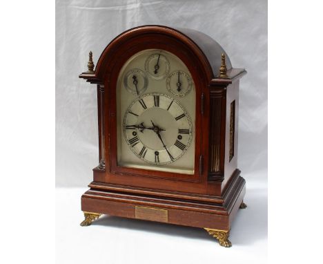 An Edwardian mahogany bracket clock of domed form with quarter stop fluted ionic columns on a plinth base and gilt metal lion