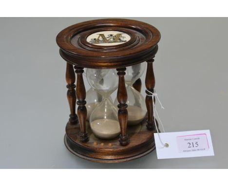 A rosewood triple hourglass timer, the three glasses within turned baluster spindles, inset to top and bottom with a ceramic 