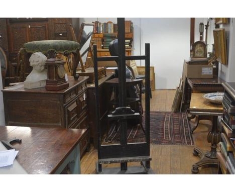 A large ebonised artist's easel, c. 1900, with adjustable top bar and deep base shelf, on a trestle base. Height 185cm