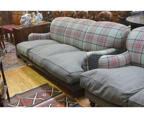 A three seater sofa, upholstered in a green tartan and tweed, with loose cushioned seat, raised on turned legs moving on bras