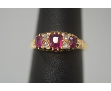 A ruby and diamond ring, early 20th century, the central cushion cut ruby flanked by a pair of oval cut rubies spaced by pair