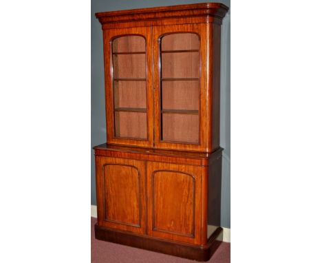 A Victorian mahogany cabinet, the flared cornice above glazed doors enclosing shelves, the base fitted two arched panel doors