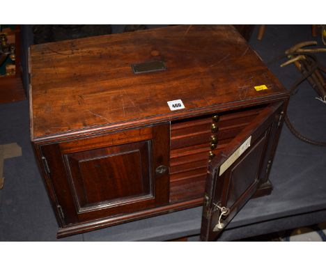 A table top mahogany coin cabinet fitted two brass carrying handles, two panelled doors opening to reveal nine drawers.